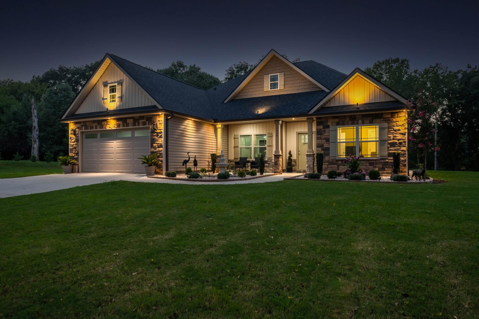 The house is lit up at night and has a large driveway.