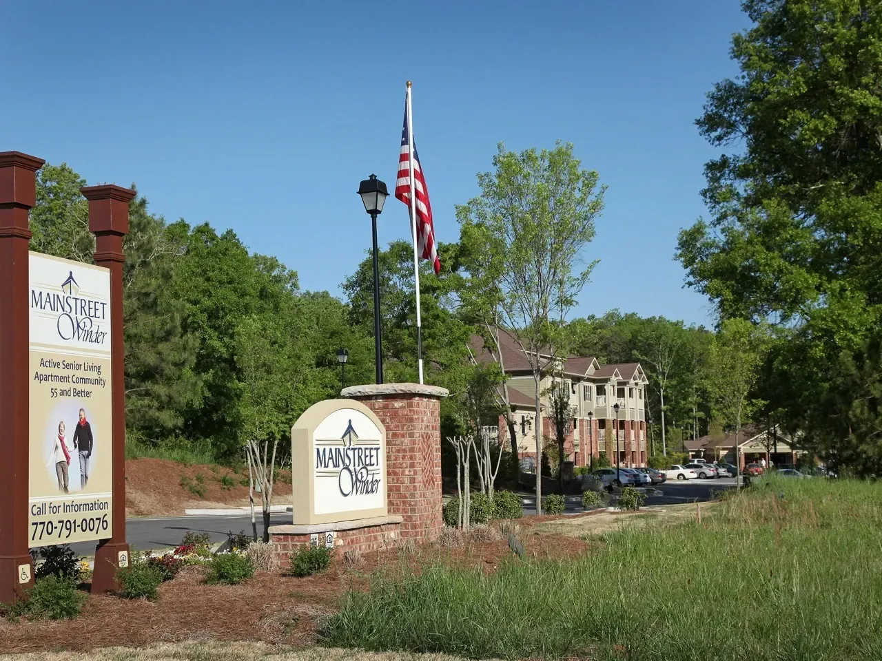 Entrance to Mainstreet Winter senior living community with brick sign and American flag.