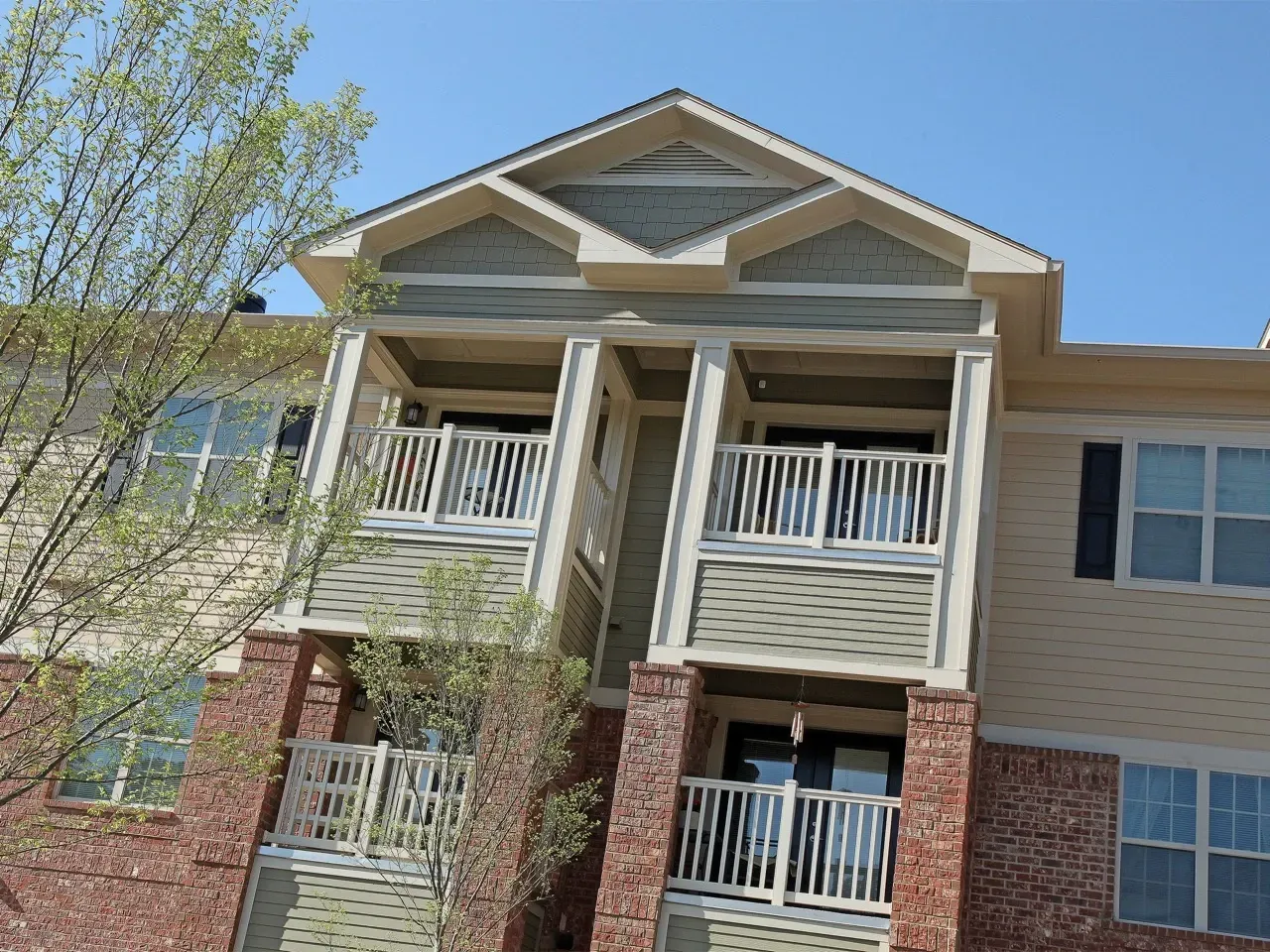 Exterior view of a modern apartment building with balconies and brick columns.