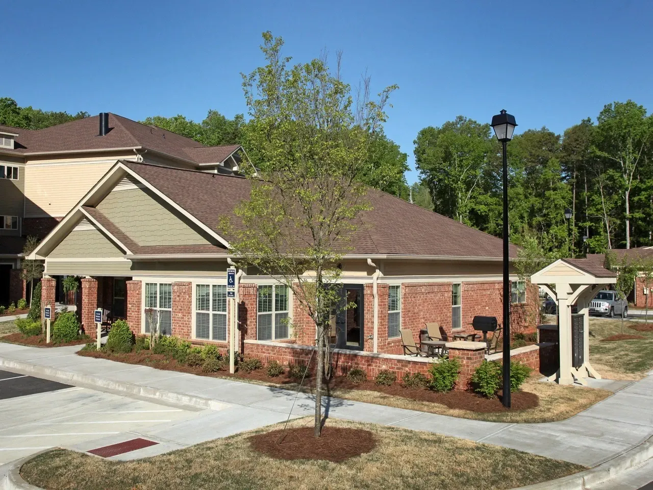 Exterior view of a brick apartment community building with a covered entrance and parking.