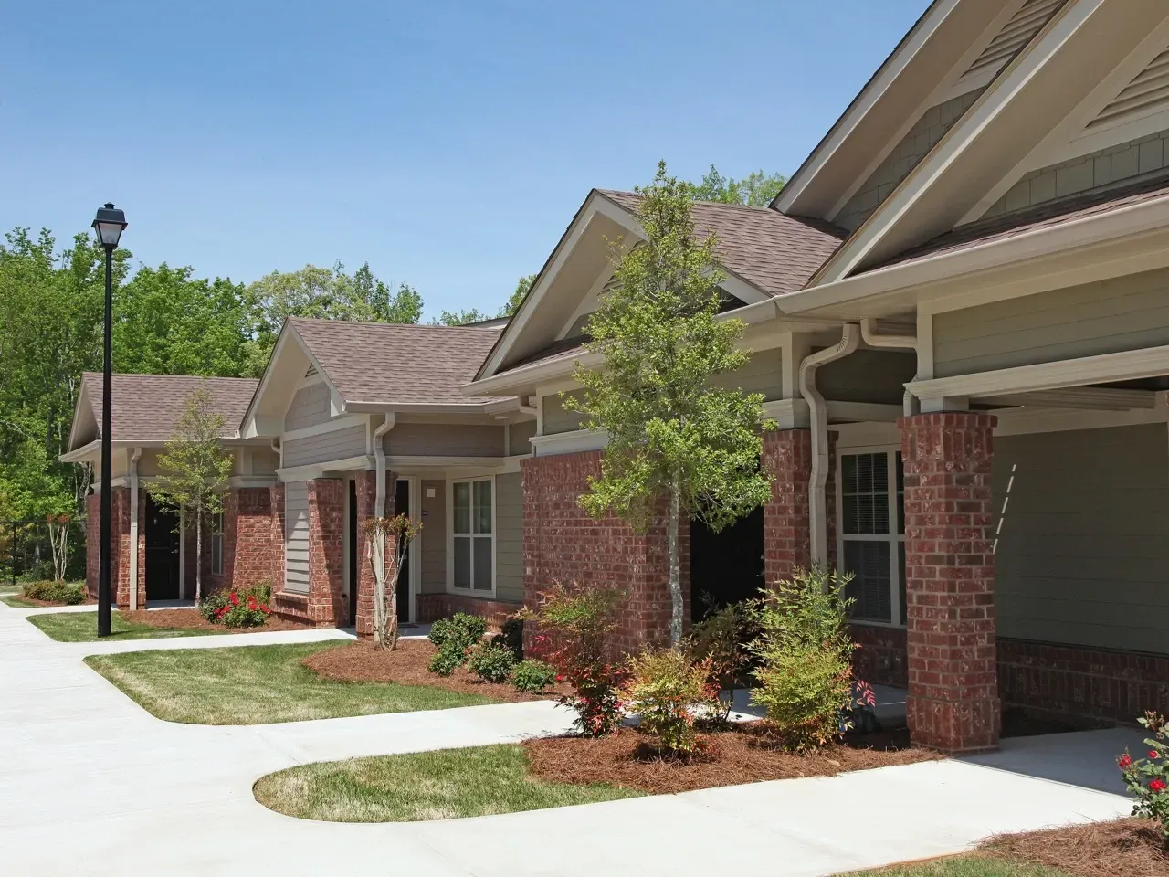 Exterior view of a multifamily community with brick columns, entryways, and landscaped walkways.