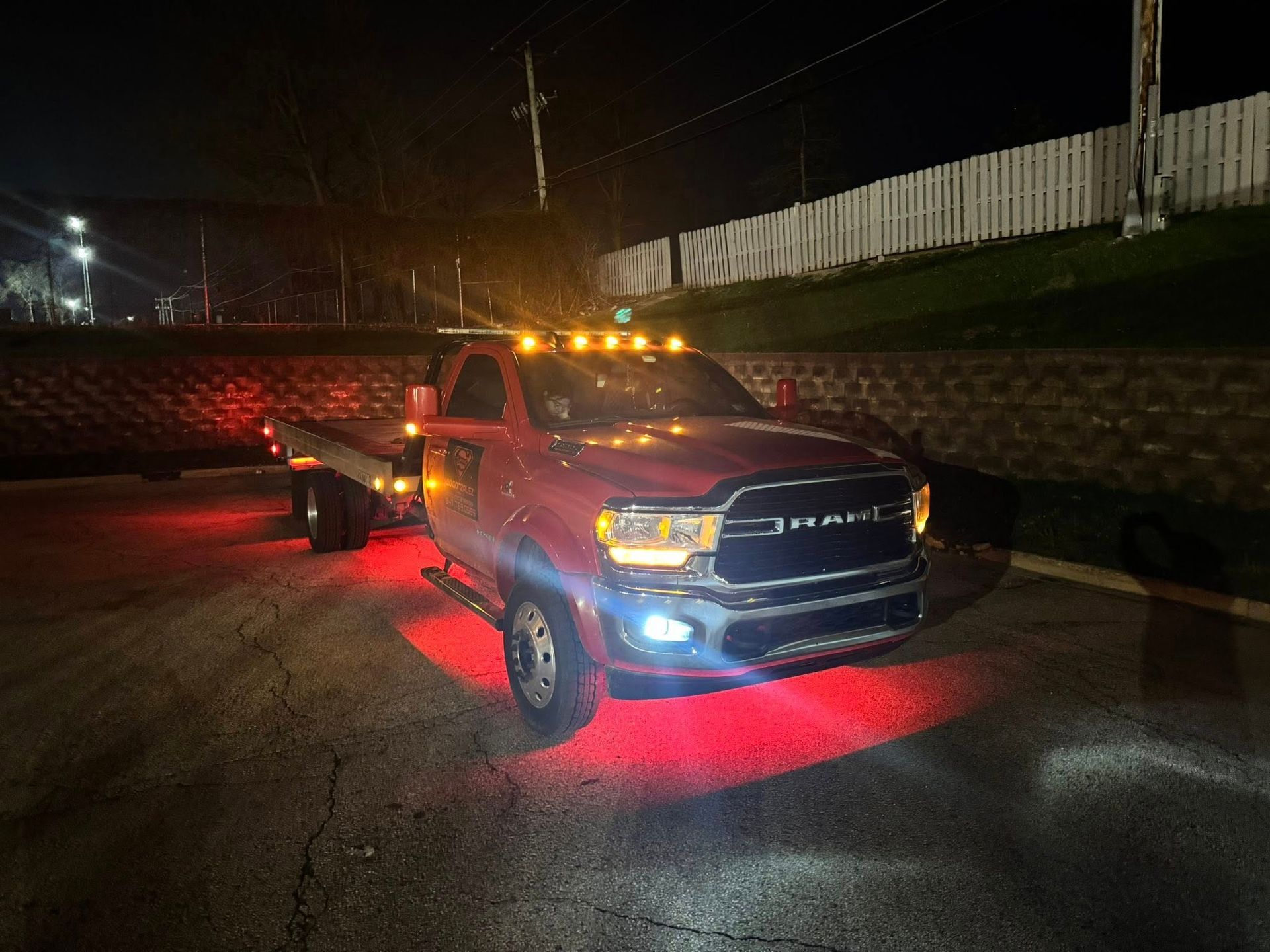 Red tow truck with lights on asphalt at night.