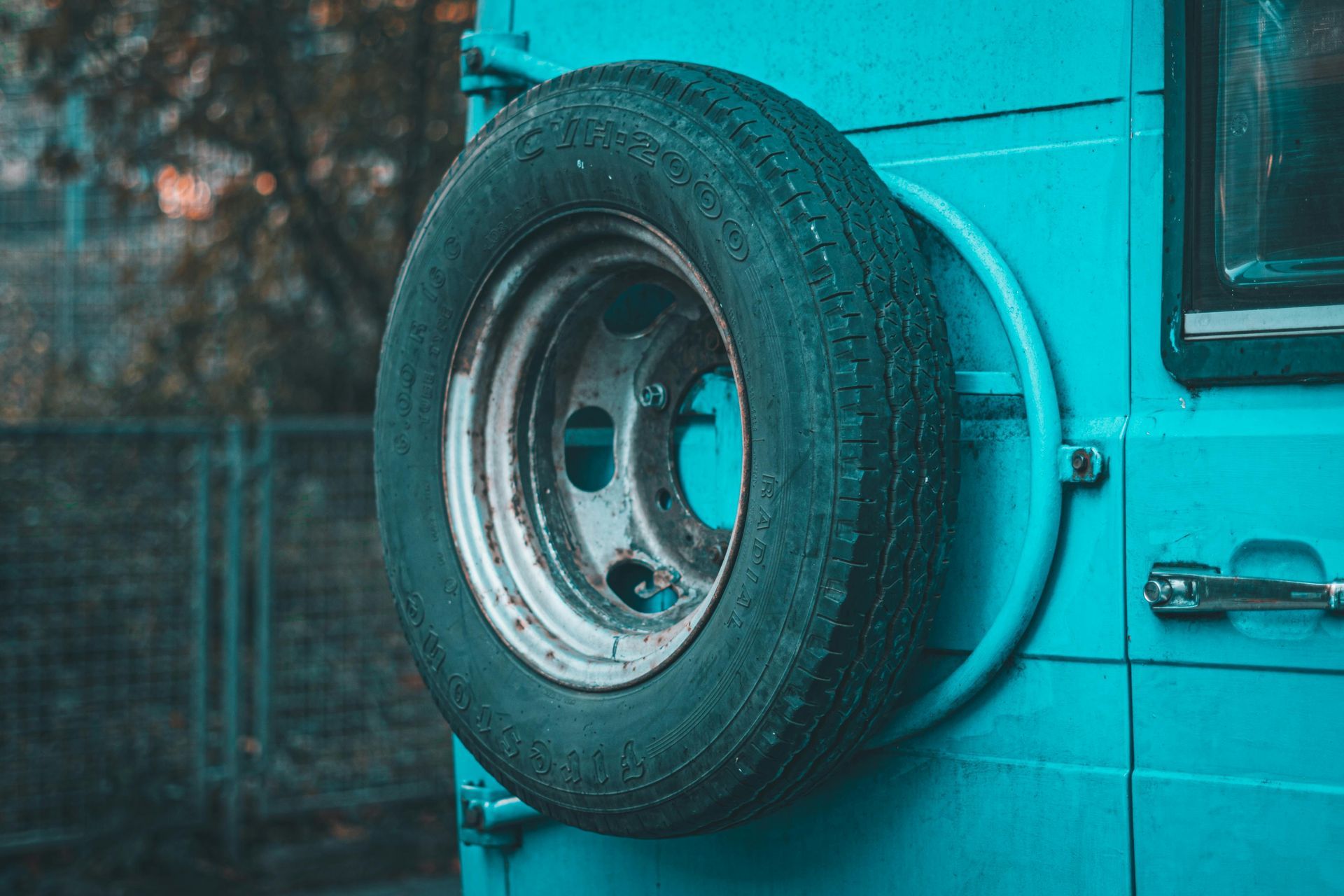 Spare tire attached to back of turquoise vehicle