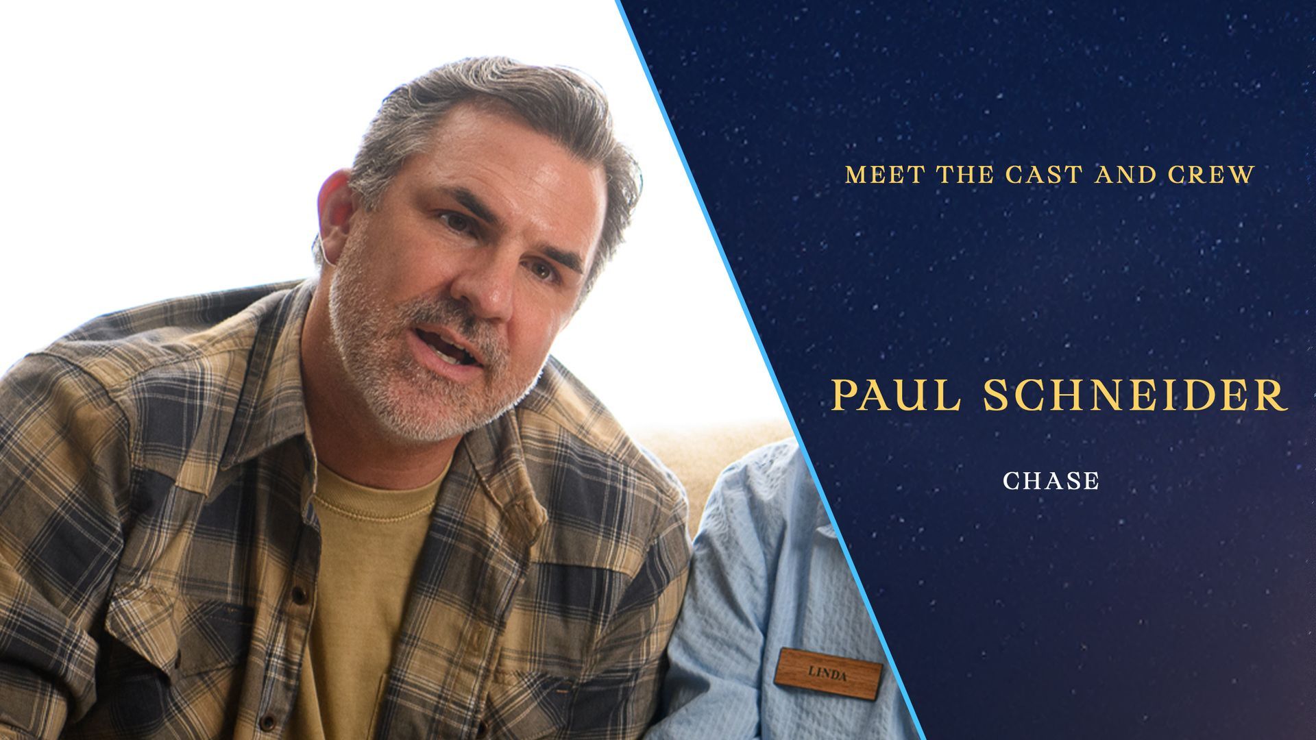 A man in a plaid shirt is sitting in front of a starry sky.