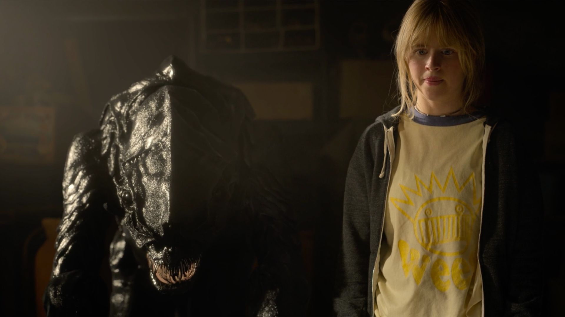 A woman is standing next to a statue in a dark room.