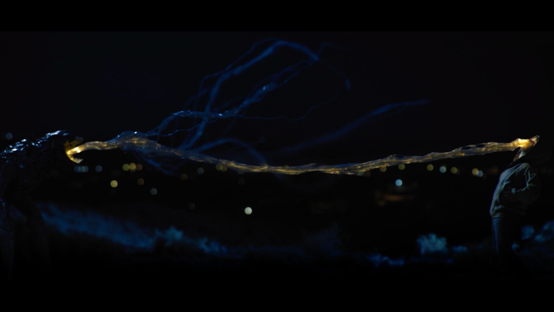 A person is standing in the dark holding a glowing object in their hand.