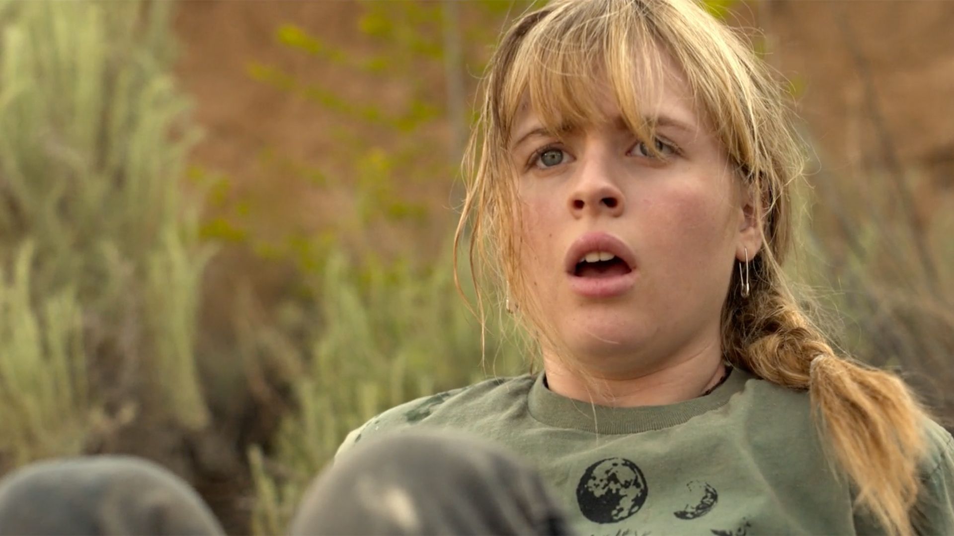 A young girl in a green shirt is making a surprised face.