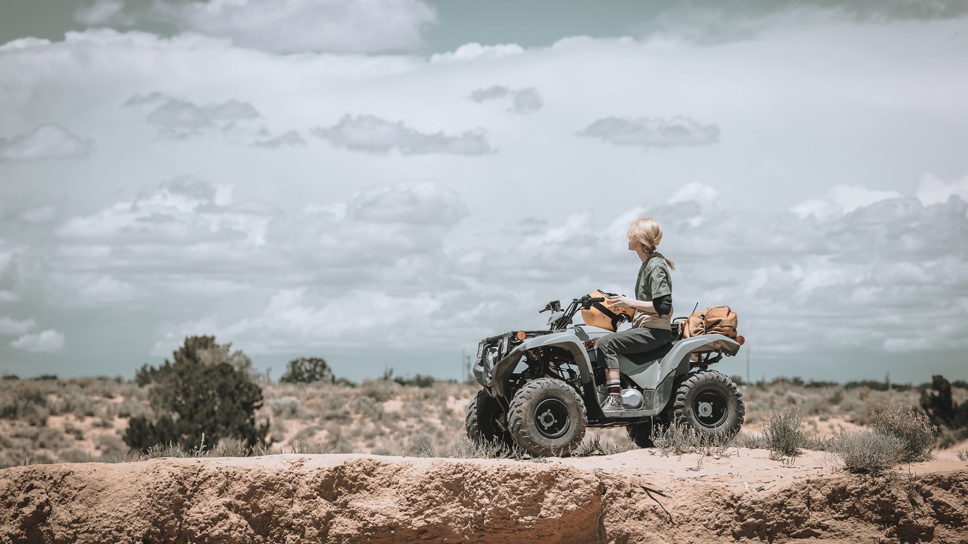 A man is riding an atv in the desert.