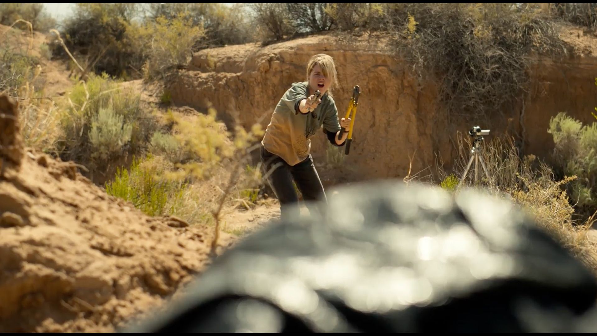 A man is standing in the dirt holding a hammer.