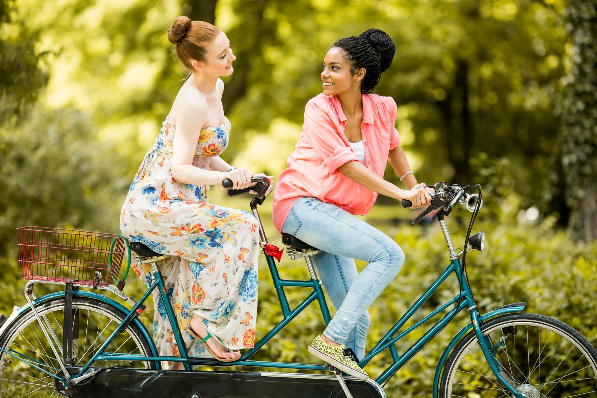 Two women are riding a tandem bike in a park