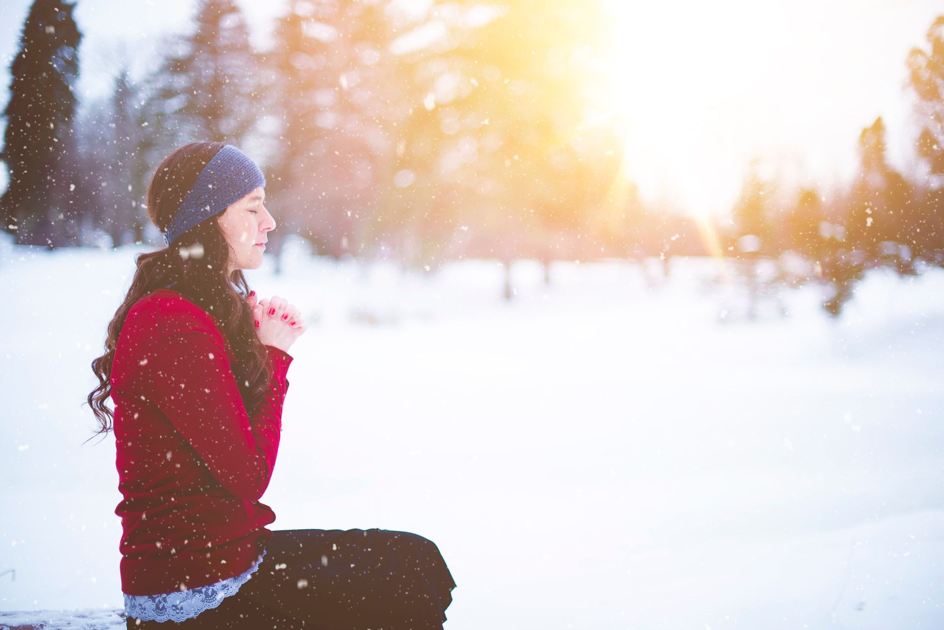 A woman in a red sweater is sitting in the snow