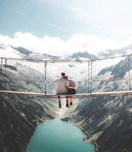 A couple sitting on a bridge overlooking a lake