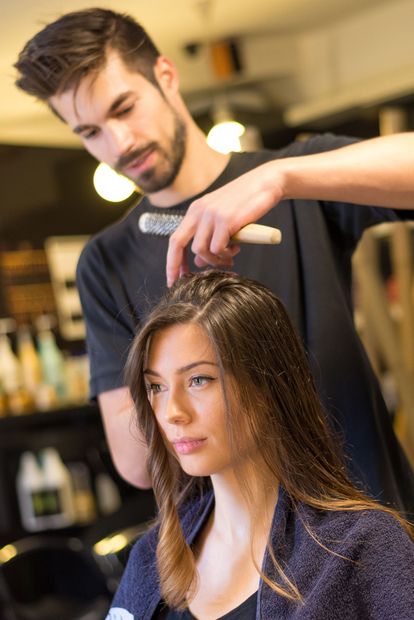 Una donna si sta facendo sistemare i capelli dal parrucchiere in un salone.