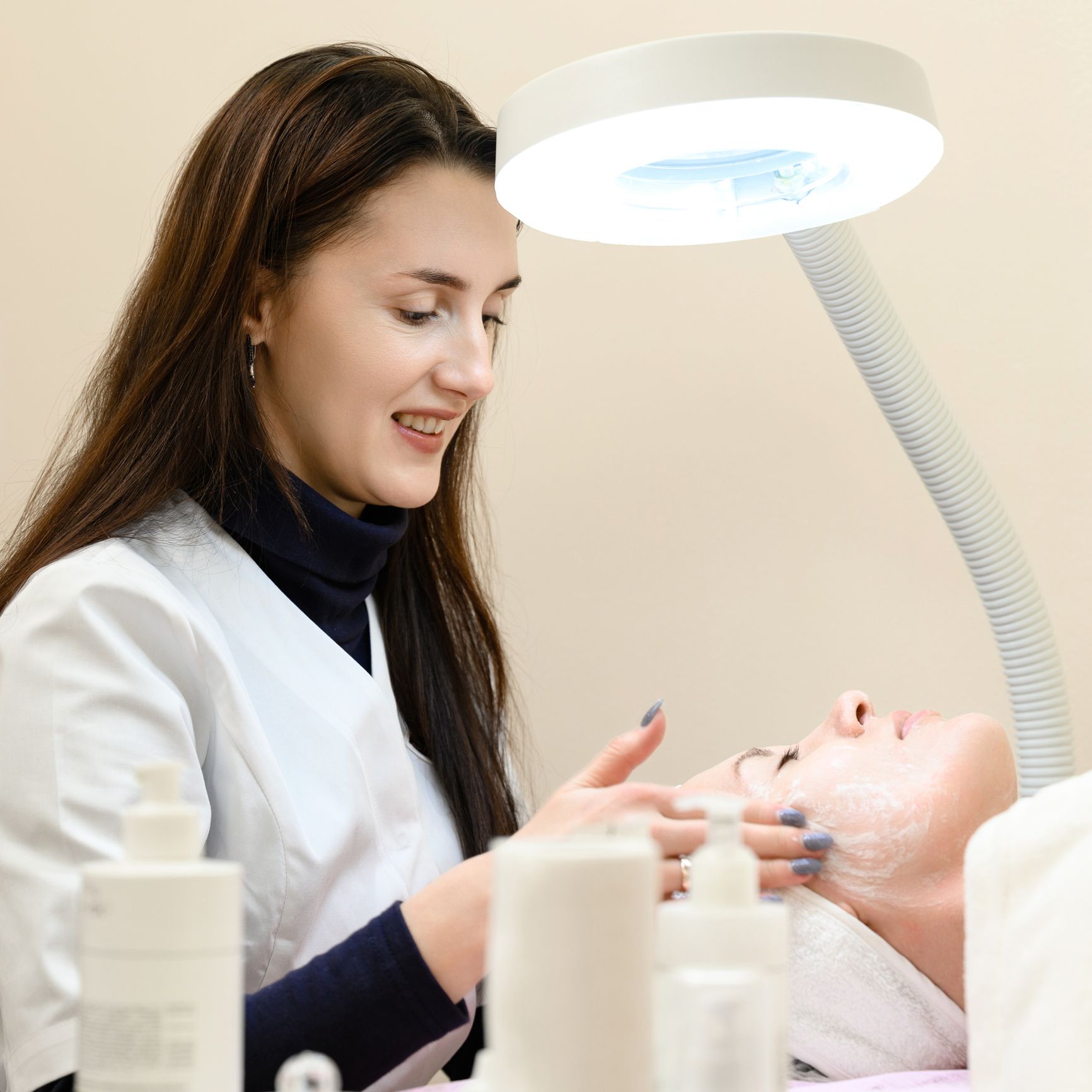 Una donna sta pulendo il viso di un'altra donna sotto una lampada.