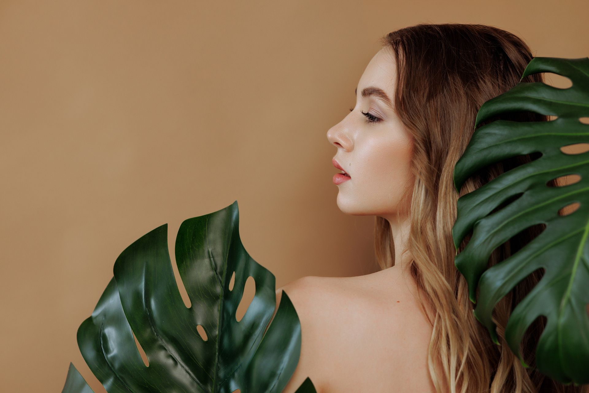 Una donna è in piedi accanto a una foglia di palma.