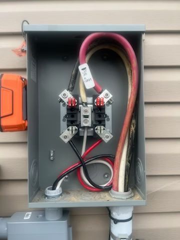 A box with wires coming out of it is on the side of a house.