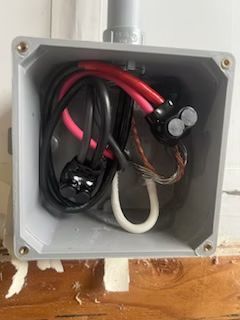 A box filled with electrical wires is sitting on a wooden floor.