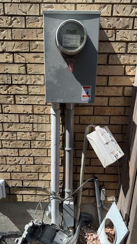 A meter is sitting on a pole in front of a brick wall.