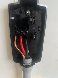 A close up of a charging station with wires coming out of it.