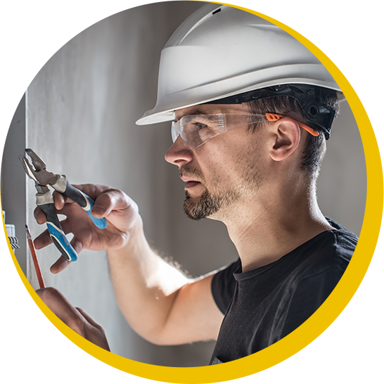 A man wearing a hard hat and safety glasses is working on a wall