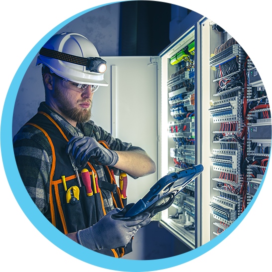 A man wearing a hard hat and safety vest is working on an electrical panel.