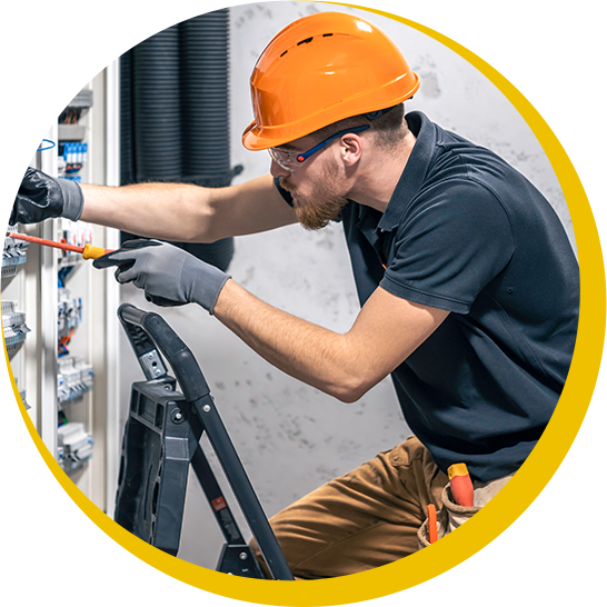 A man wearing an orange hard hat is working on an electrical panel.