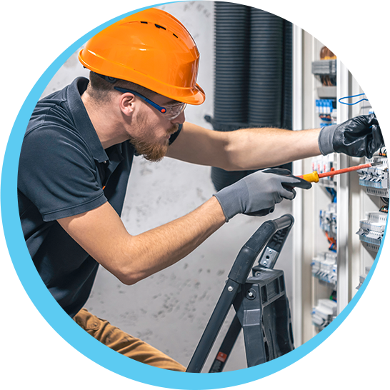 A man wearing an orange hard hat is working on an electrical panel.