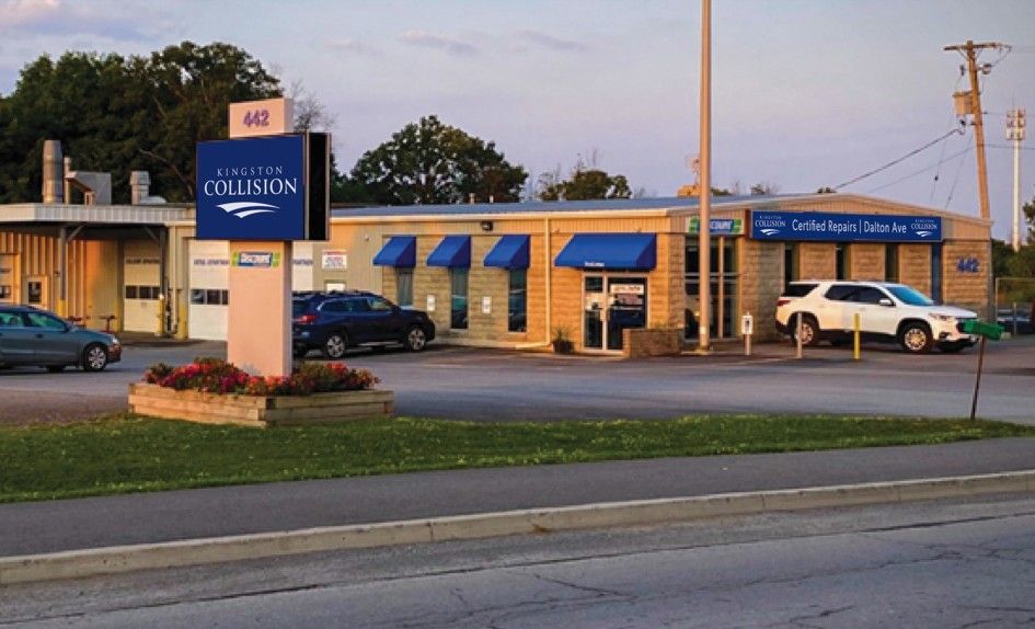 A blue and white auto body shop with sign and cars.
