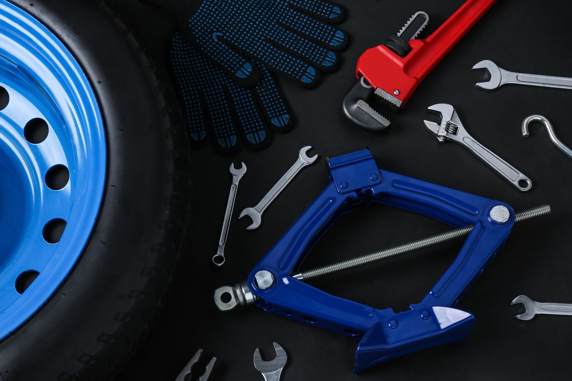a blue tire is surrounded by tools and gloves on a black surface .