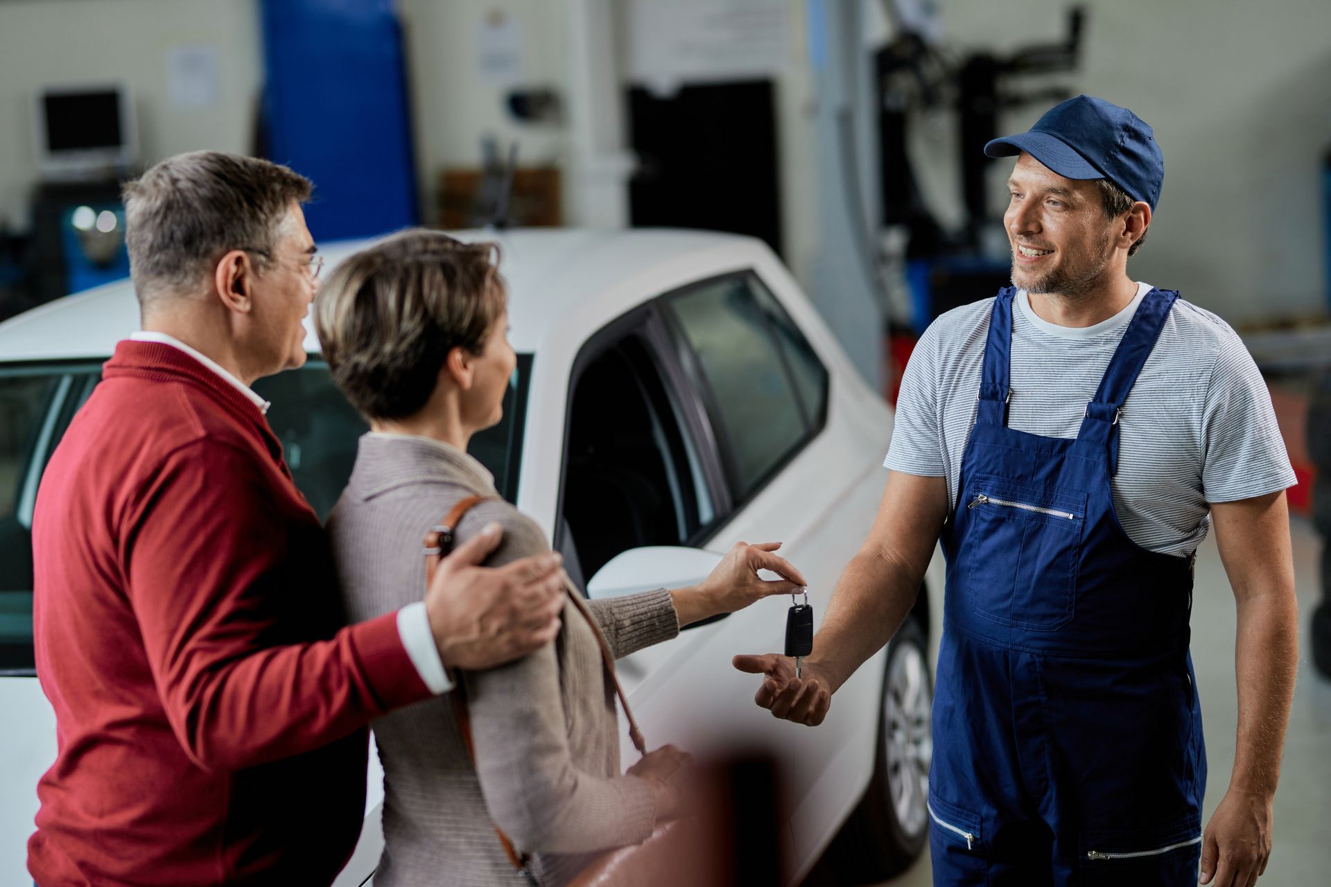 a man is giving a woman a car key in a garage .