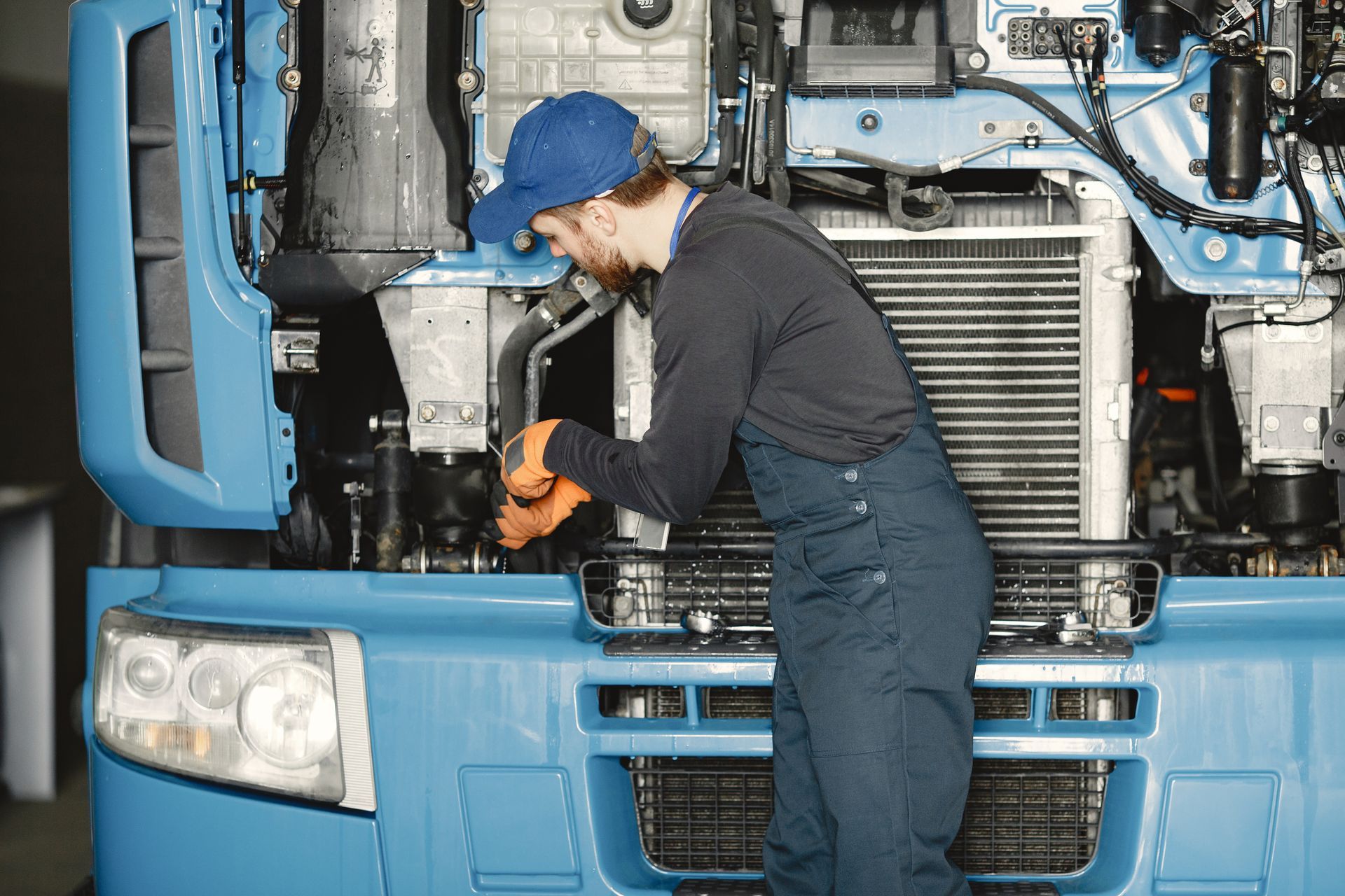 A man is working on the engine of a blue truck.