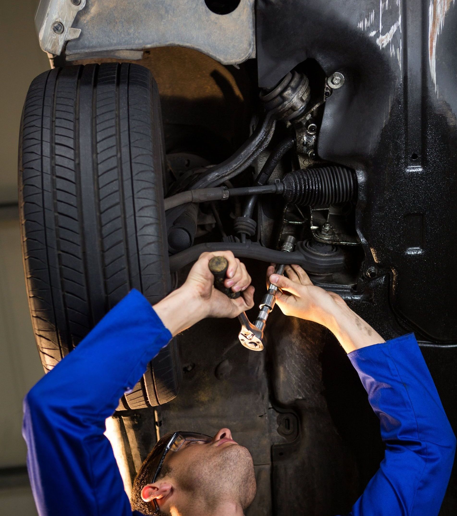 a man is working under a car with a wrench .