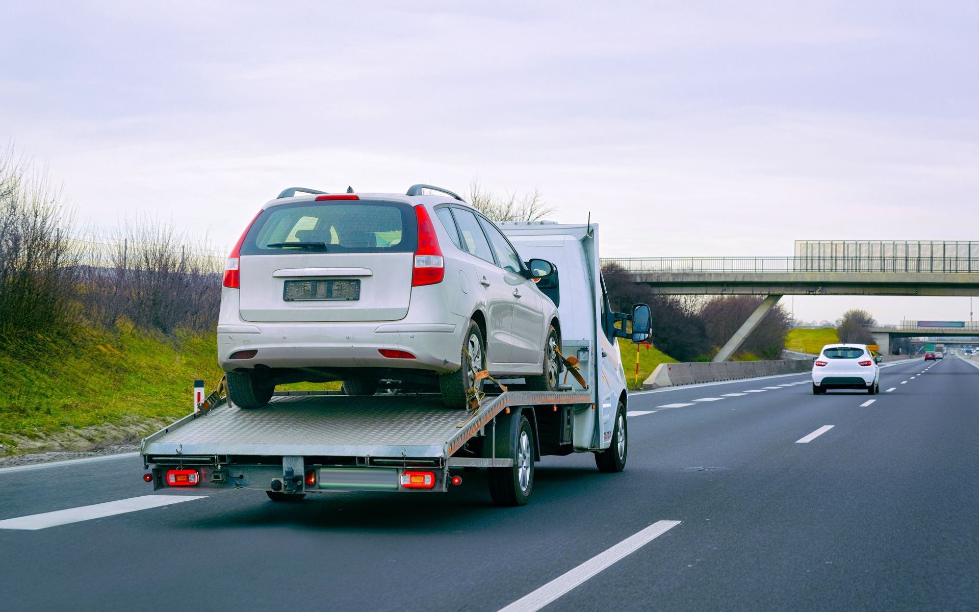 a tow truck is towing a white suv on a highway .