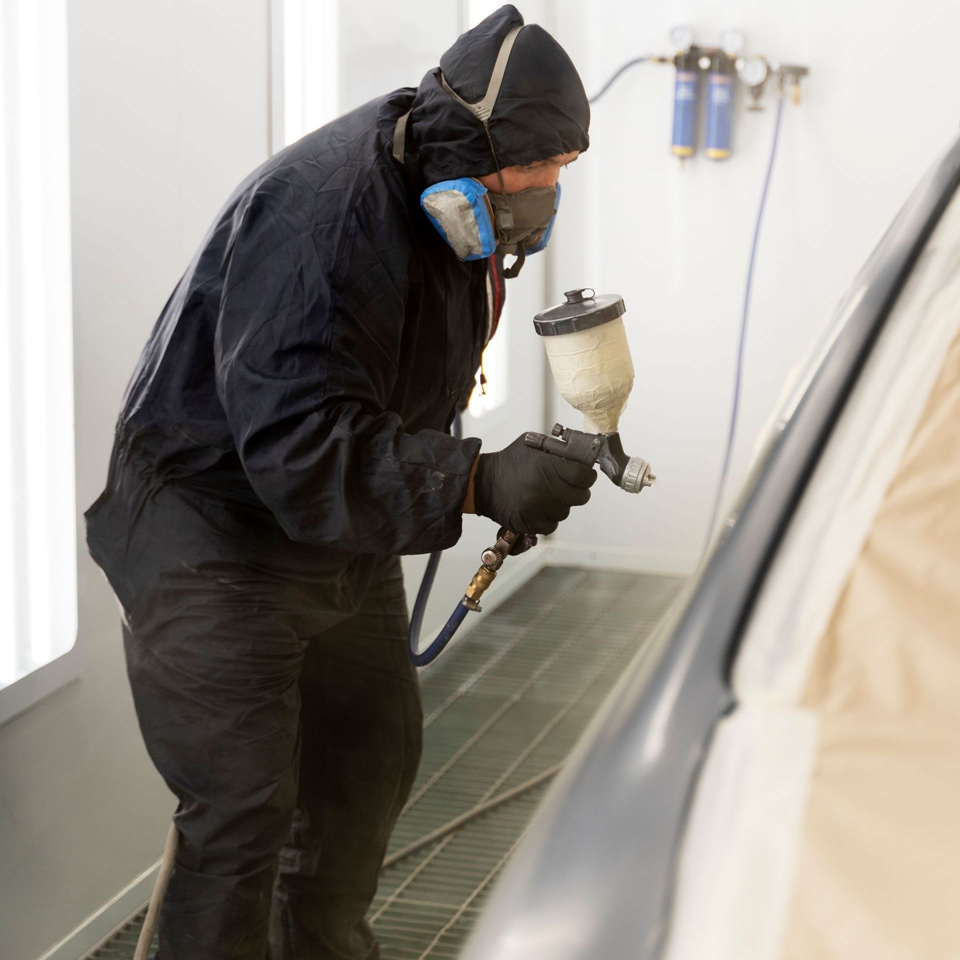 a man wearing a mask is spray painting a car