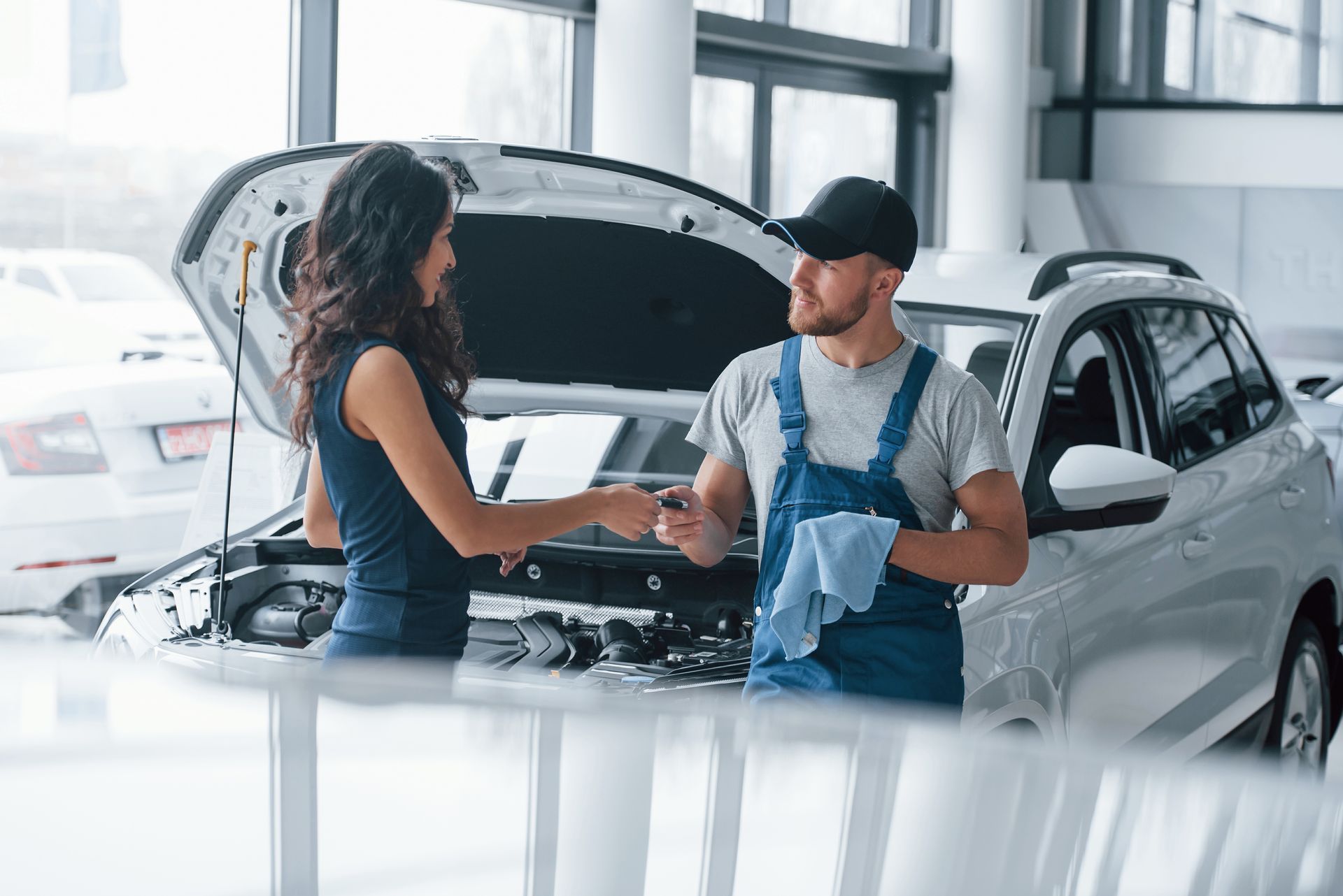 A man and a woman are shaking hands in front of a car.