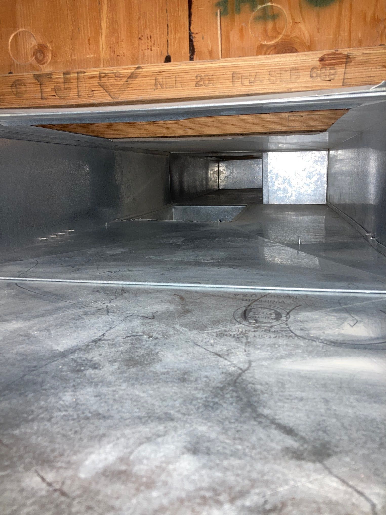 A close up of a metal duct under a wooden ceiling.