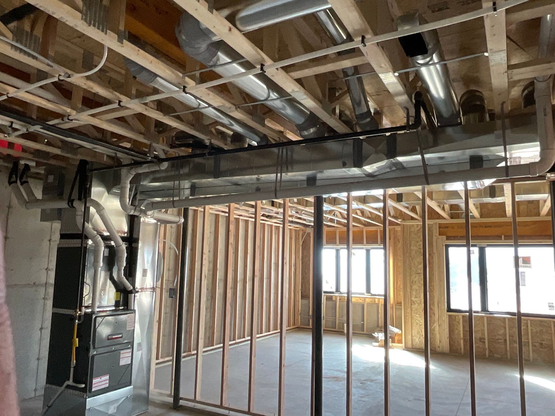 A room under construction with a lot of pipes hanging from the ceiling.