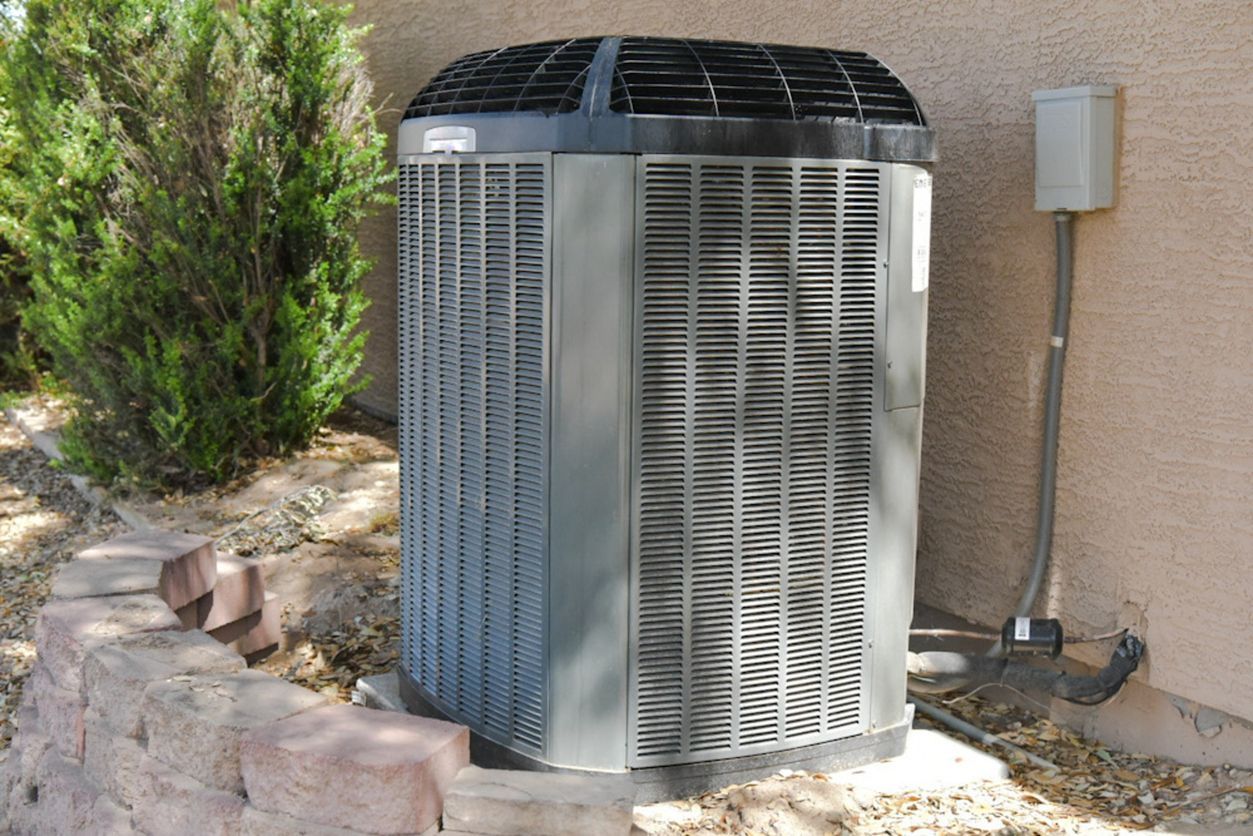 A large air conditioner is sitting on the side of a building.