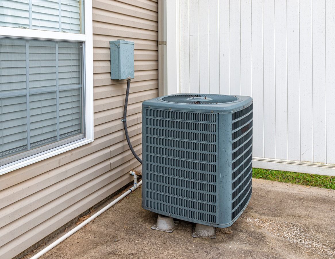 An air conditioner is sitting on the side of a house next to a window.