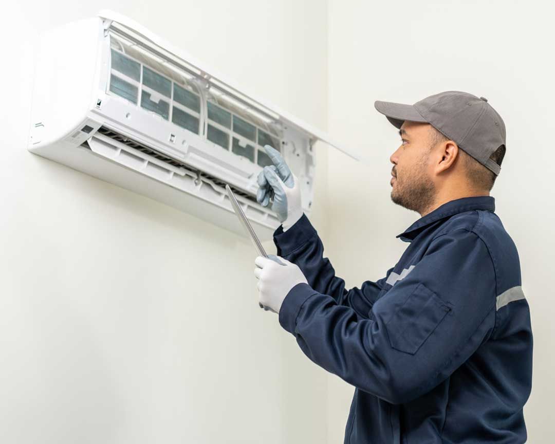 A man is cleaning an air conditioner with a wrench.