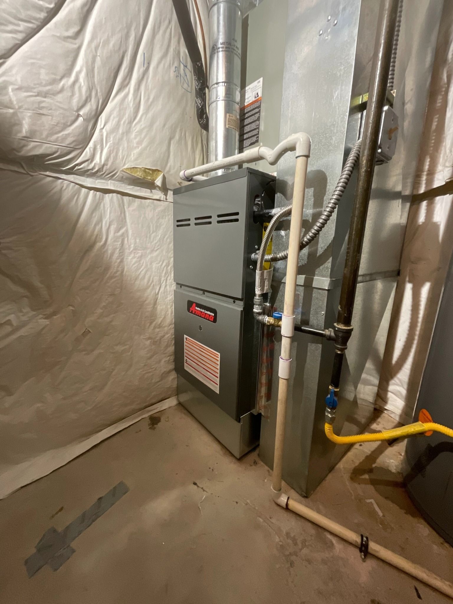A gas heater is sitting in a basement next to a wall.