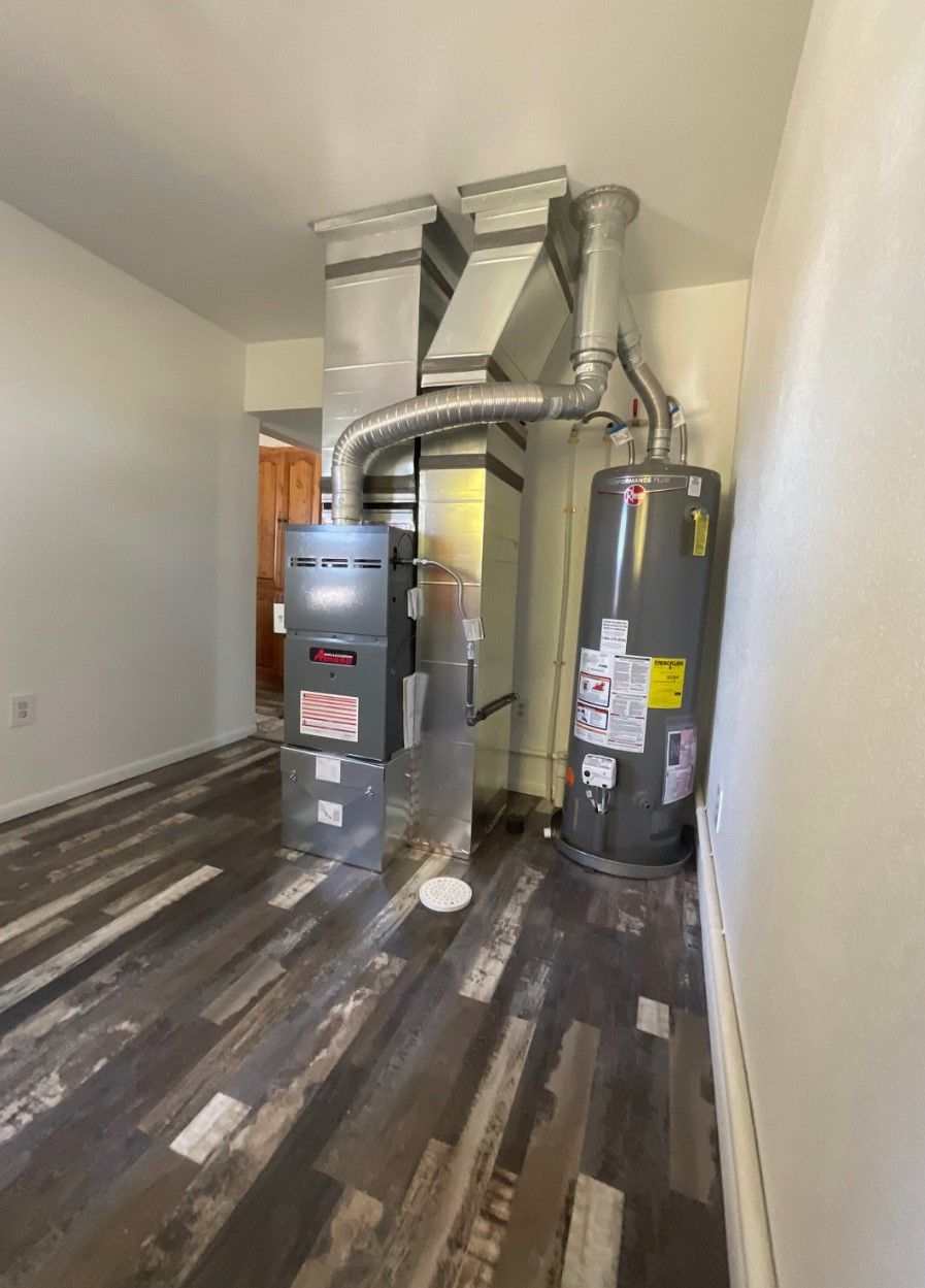 A room with a water heater and a furnace in it.
