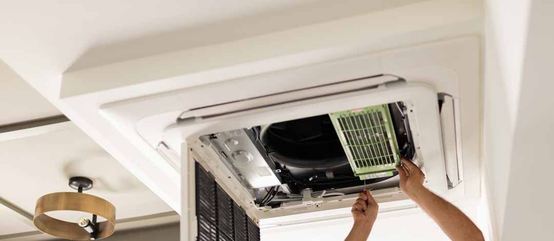A man is working on an air conditioner in a room.