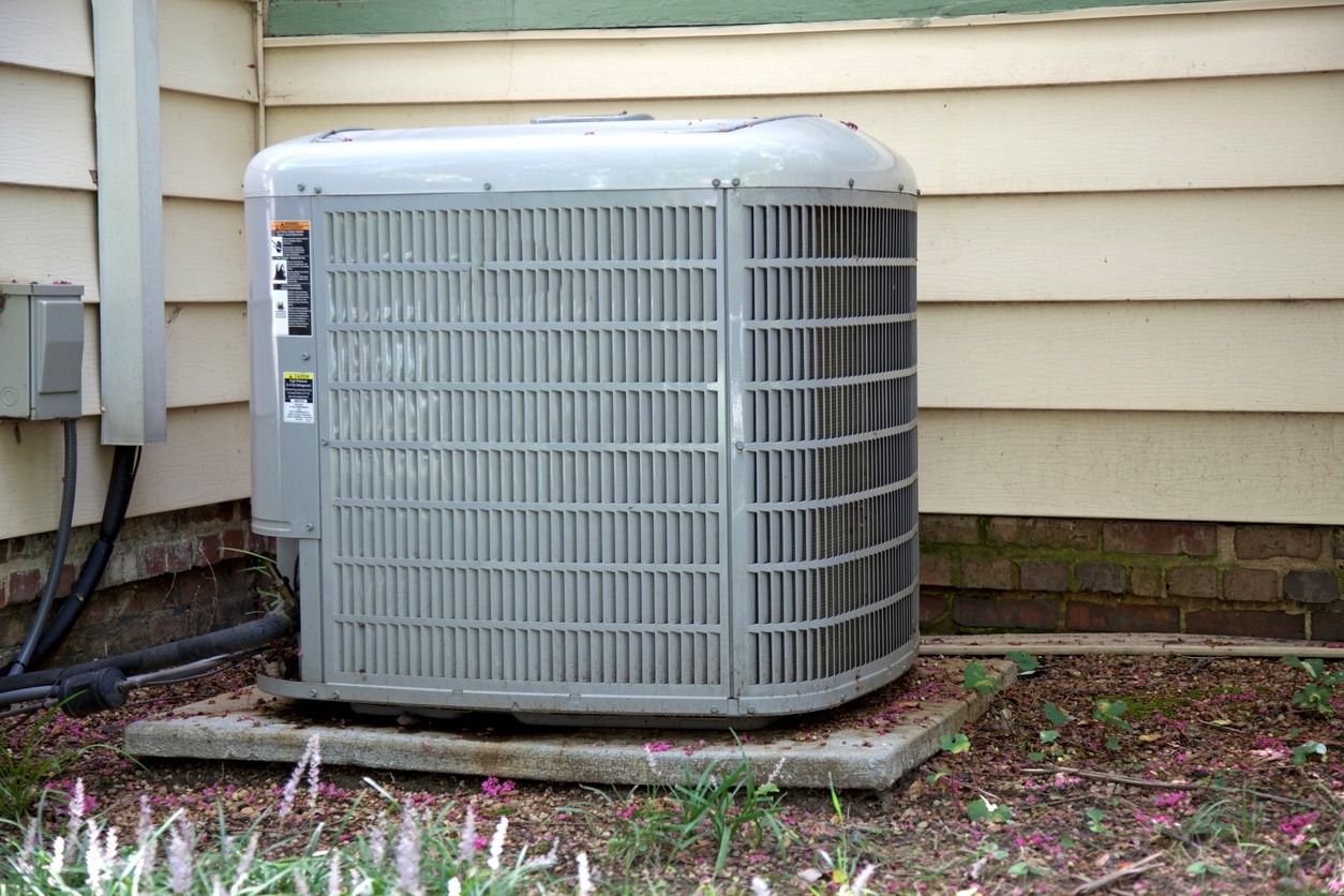 A large air conditioner is sitting outside of a house.