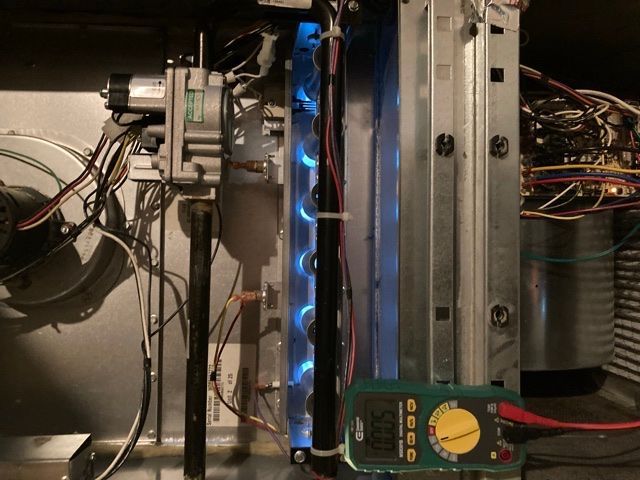 A green multimeter is sitting next to a computer