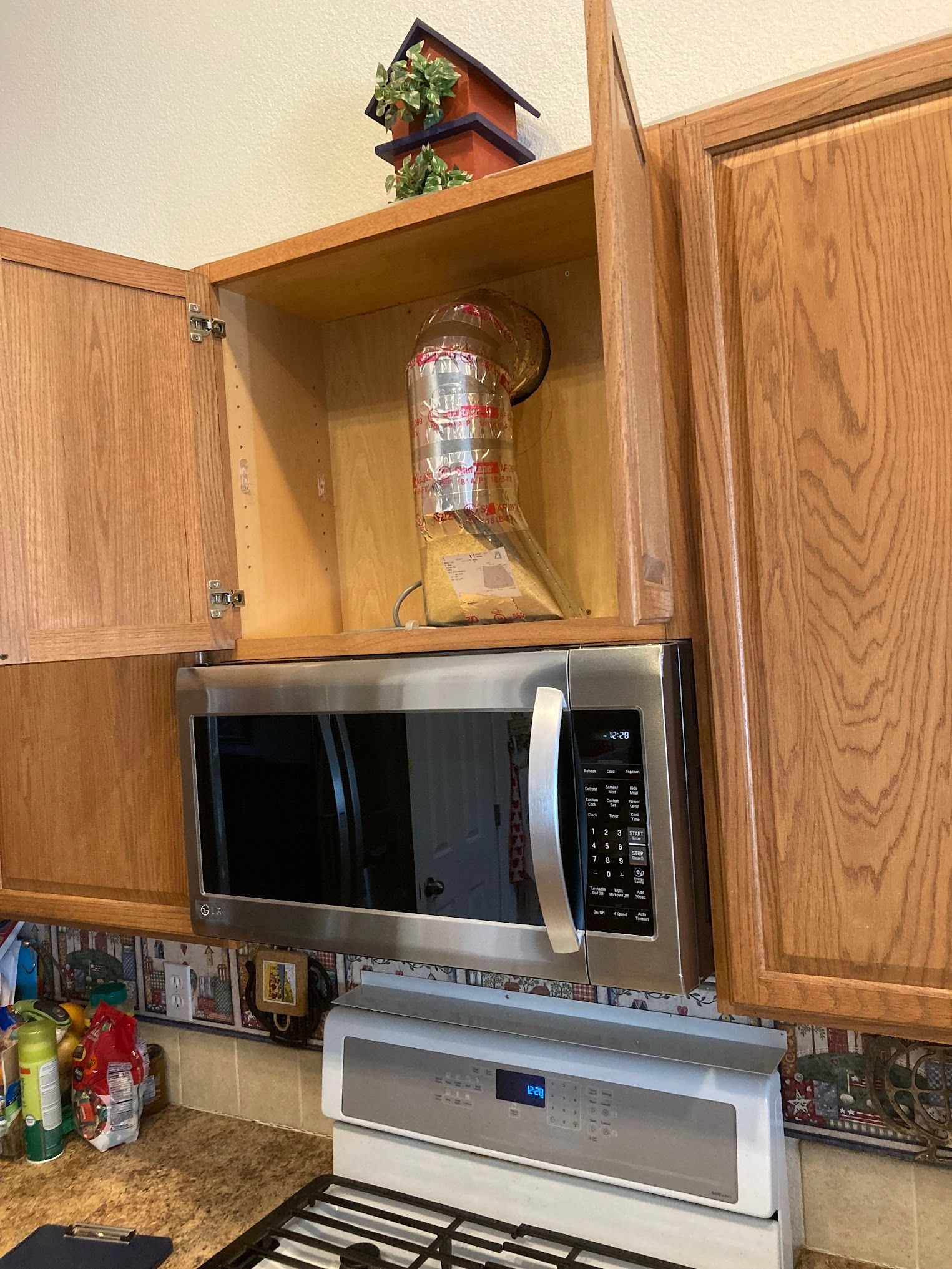 A microwave oven is sitting on top of a wooden cabinet in a kitchen.