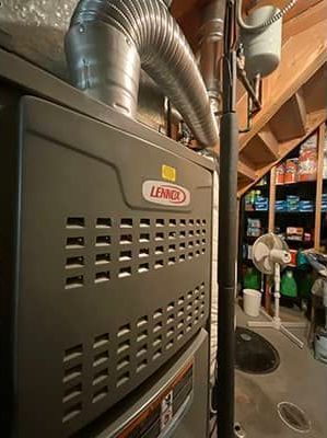 A lennox furnace is sitting in a basement next to a fan.