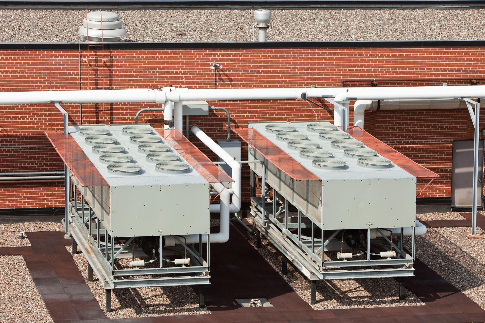 Two air conditioners are sitting on the roof of a building.