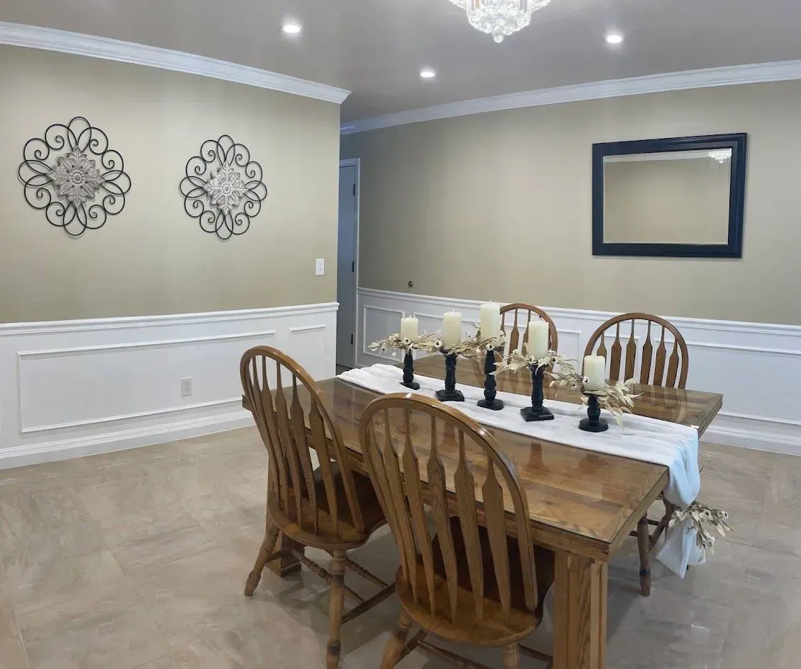 Dining room with wooden table and chairs, candles, decorative wall art, and mirror.
