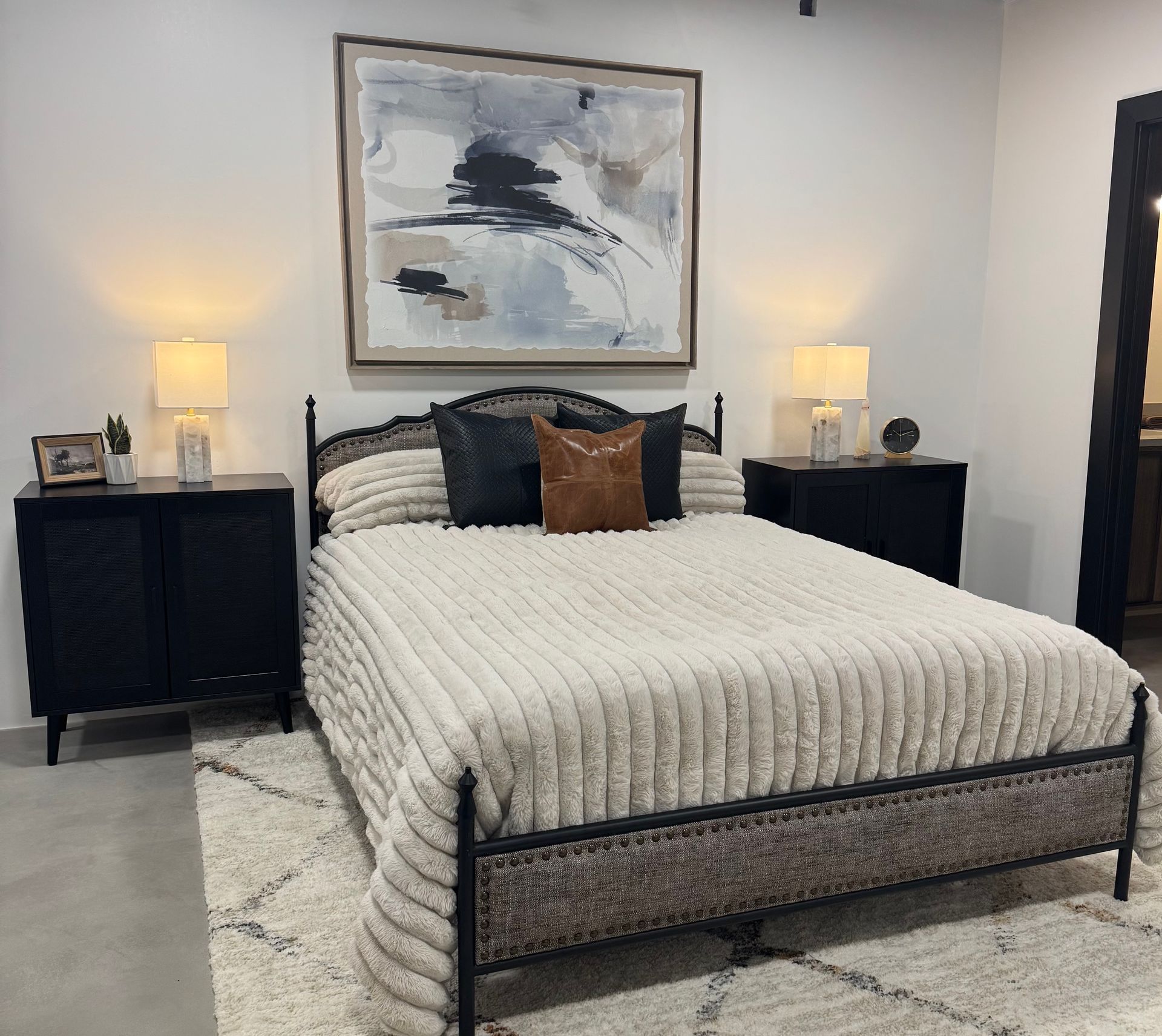 Bedroom with bed, nightstands, rug, and artwork.  Neutral color palette.